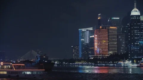 Skyscrapers and a boat floating on the river in Shanghai by night Stock Footage 99367204