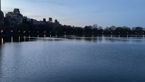 Skyscrapers reflect dramatically in waters of Central Park during last light NYC Video stock 195131642