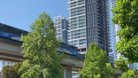 Skytrain passing by trees and condos Stock Footage 282083866