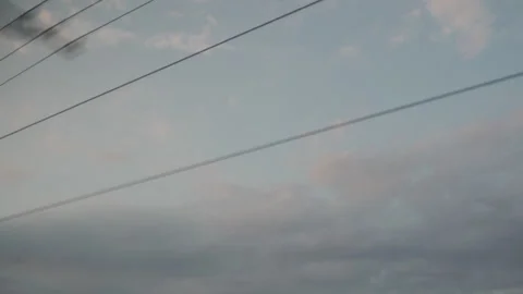 Skyward Gaze: Power Lines Etch a Serene, Cloud-Dappled Vista from a Moving Train Stock Footage 318477215