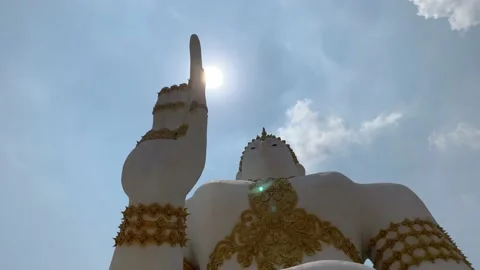 Skyward shot of sun emerging from pointing finger of Buddha Stock Footage 171846335