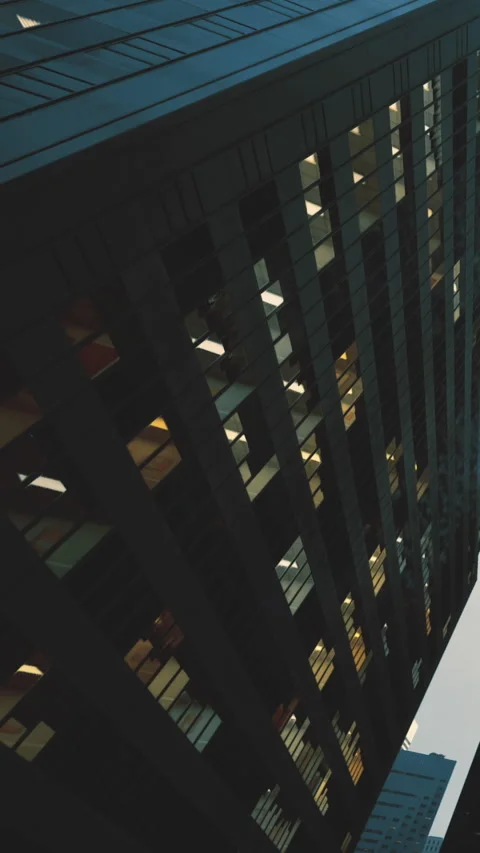 Skyward view of tall building with glowing windows in the early evening Stock Footage 331684047