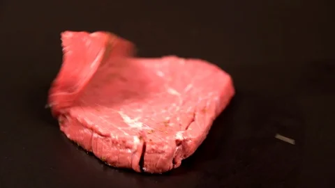 Slab of tender lean raw steak falling onto black Video stock 105110449