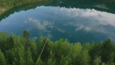 Slackline balanced walk over large chasm of pristine water and woods. High 8 Stock Footage 158402707