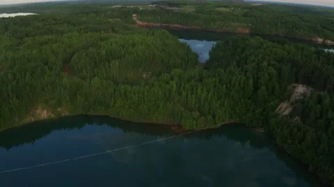 Slackline balanced walk over large chasm of pristine water and woods. High shot. Stock Footage 158402866