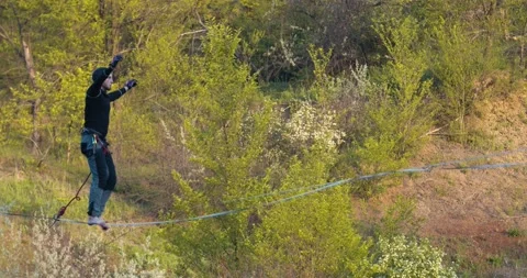 Slackline is bouncing up and down while a man is walking on it, 4k Stock Footage 133557415