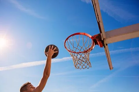 Slam Dunk. Side view of young basketball player making slam dunk Stock Photos