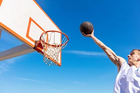 Slam Dunk. Side view of young basketball player making slam dunk Stock Photos