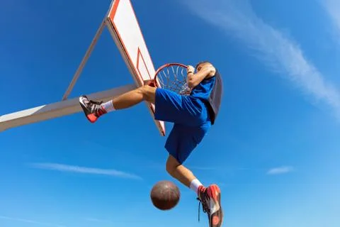 Slam Dunk. Side view of young basketball player making slam dunk Stock-Fotos