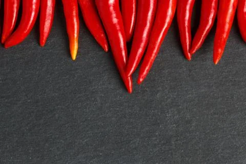 Slate background with red hot chilli peppers. Stock Photos