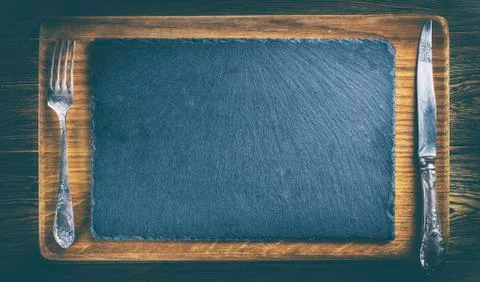 Slate flat plate, Cutlery. Wooden table. oak Board. Space for text, top view. Stock Photos