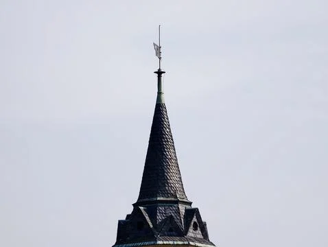 Slate Tower Cuts Through Pale Daytime Sky. Weathered Roof With Sleek Geomet.. Stock Photos