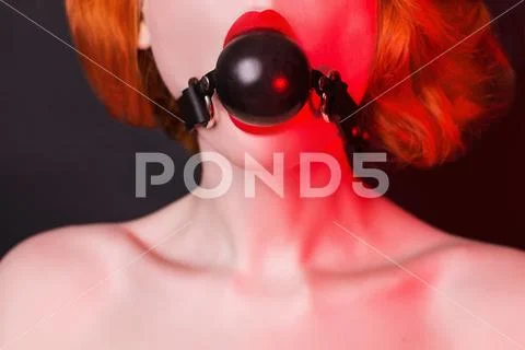 Slavery in society. Redhead hostage girl with gag on black. Sexual bdsm toy. Stock Photos