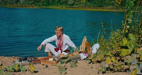 Slavic man burning ritual fire on river shore, culture and religion of ancient Stock-Footage 258514620