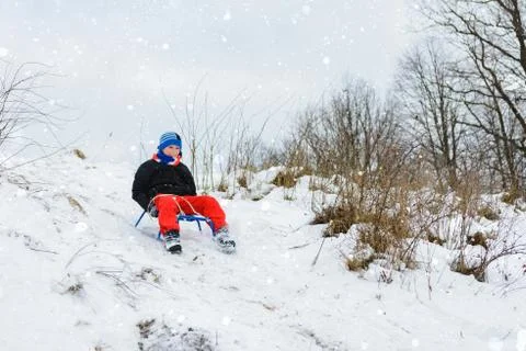 For a sledge down the boy in red pants is very happy Foto stock