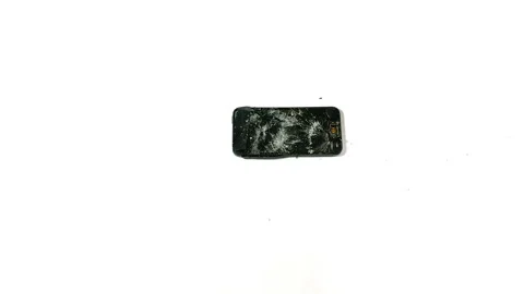 A sledgehammer falls horizontally toward a smashed Smartphone. Video stock 150267919