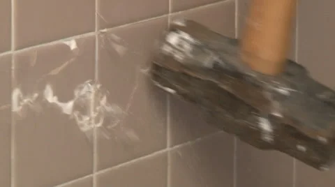 Sledgehammer head repeatedly pounds tile wall during demolition Stock Footage 39910397