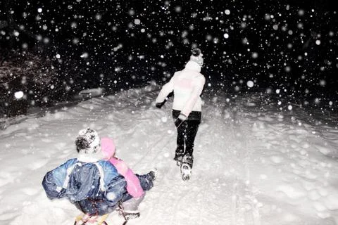 Sledges with children attached pulled on snow by woman in the winter Stock Photos