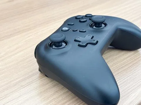 Sleek Black Wireless Gamepad Controller on Wooden Background Foto stock
