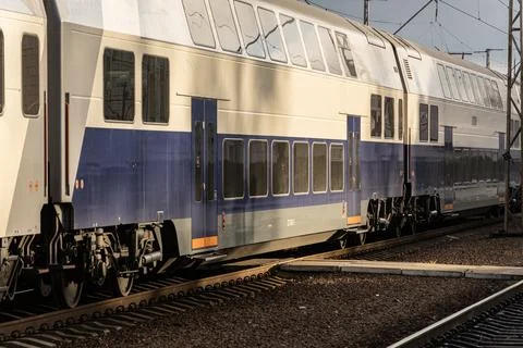 A sleek double-decker train is parked at the station, illuminated by warm l.. Stockfoto's