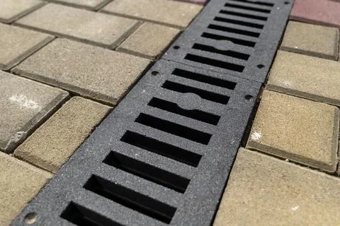 A sleek drainage grate blends seamlessly with the stylish brick pavement un.. Stock Photos