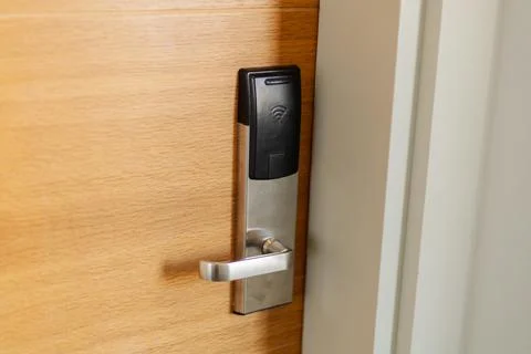 A sleek electronic door lock is mounted on a smooth wooden door. This keyless Stock Photos