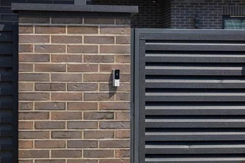 A sleek intercom device is installed on a stylish brick wall, facilitating .. Stock Photos