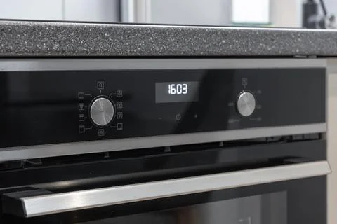 Sleek modern kitchen oven with a digital clock displaying the time 16:03, a.. Stock Photos