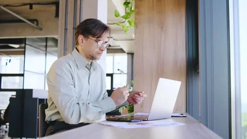 In a sleek, modern office setting, a dedicated businessman professional is Stock Footage 292637849