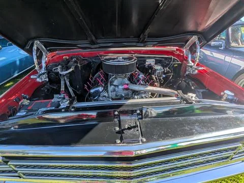 A sleek red custom car with its hood raised shows a round supercharger Stock Photos