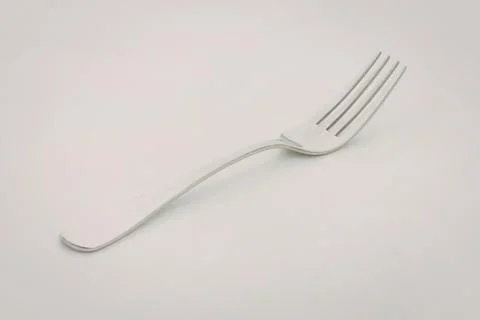 Sleek silver fork on plain surface Stock Photos