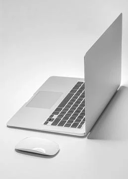 A sleek silver laptop and a white wireless mouse are positioned on a white Stock Illustration