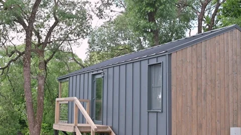 A sleek structure stands in a wooded area, showcasing a balance of wood and Video stock 339004481