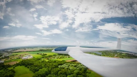 A sleek, white glider soars gracefully over a picturesque landscape beneath.. Stock Footage 310595834