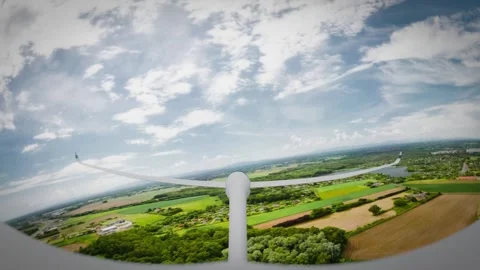A sleek, white glider soars gracefully over a picturesque landscape beneath.. Stock Footage 310626853
