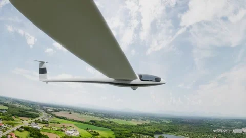 A sleek, white glider soars gracefully over a picturesque landscape beneath.. Stock Footage 310666339