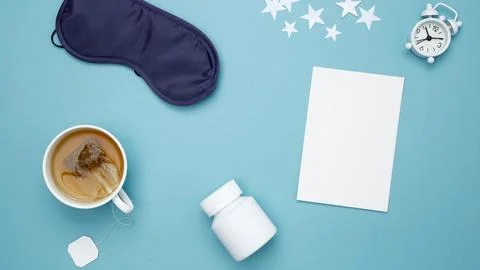 Sleep essentials eye mask, tea, pills, mock up white paper. Concept of relaxa Stock Photos