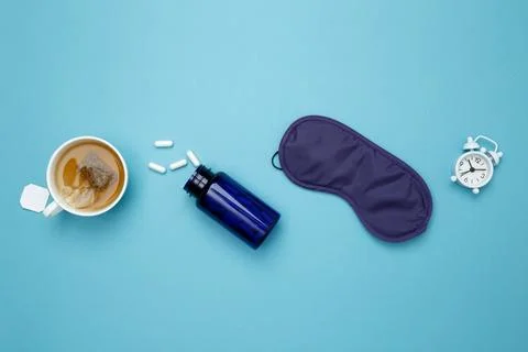 Sleep essentials eye mask, tea, pills, clock. Concept of relaxation and rest, Stock Photos