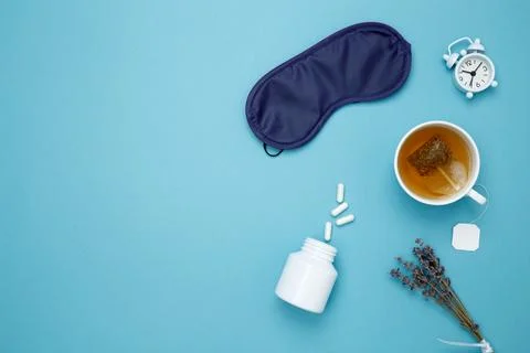 Sleep essentials eye mask, tea, pills, clock. Concept of relaxation and rest, Stock Photos