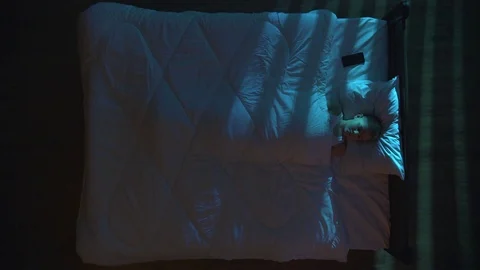 The sleeping boy lie on the bed and phone. Evening night time. View from above Video stock 71966149