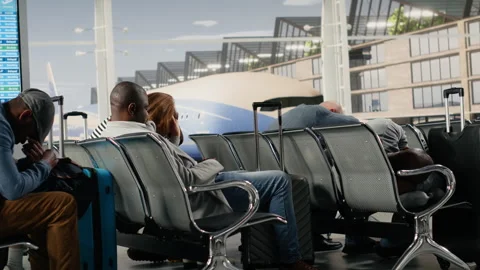 Sleeping, flight delay concept and exhausted tourists on bench in busy airport Stock Footage 333653203