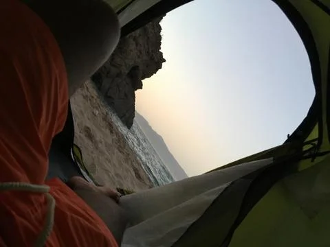 Sleeping inside a tent facing the beach under the sunset Stock Photos