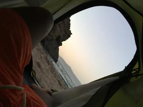 Sleeping inside a tent facing the beach under the sunset Stock Photos