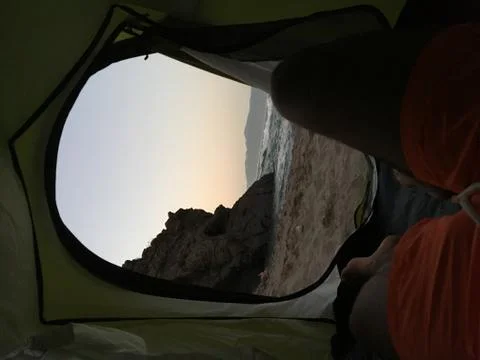Sleeping inside a tent facing the beach under the sunset Stock Photos