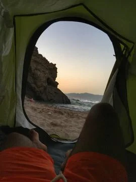 Sleeping inside a tent facing the beach under the sunset Stock Photos