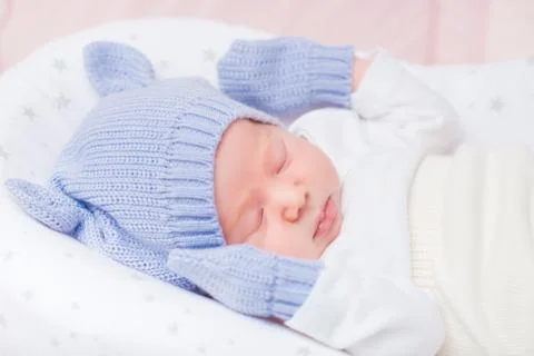 Sleeping little baby wearing knitted blue hat with ears and mittens Stock Photos