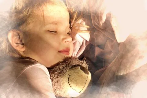 Sleeping little girl in pjamas with teddy bear lie down on bed while sun shin Stock Photos