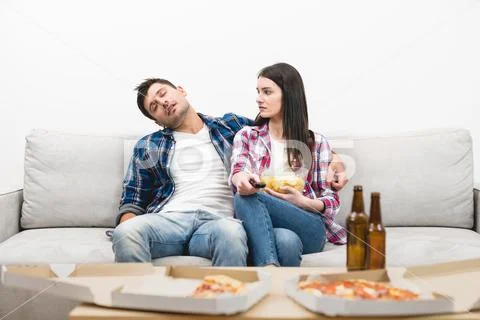 The sleeping man and a woman sit on the sofa on the white wall background Stock Photos