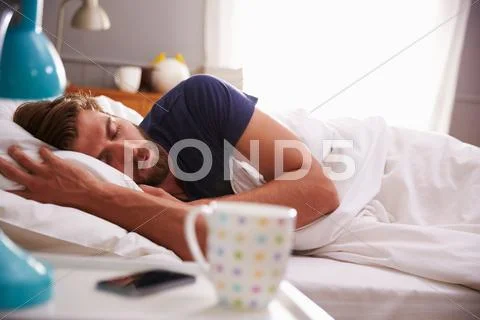 Sleeping Man Being Woken By Mobile Phone In Bedroom Stock Photos