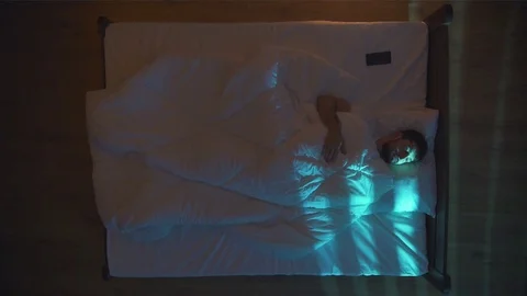 The sleeping man lay on the bed and phone. Evening night time. View from above Stock Footage 71964869